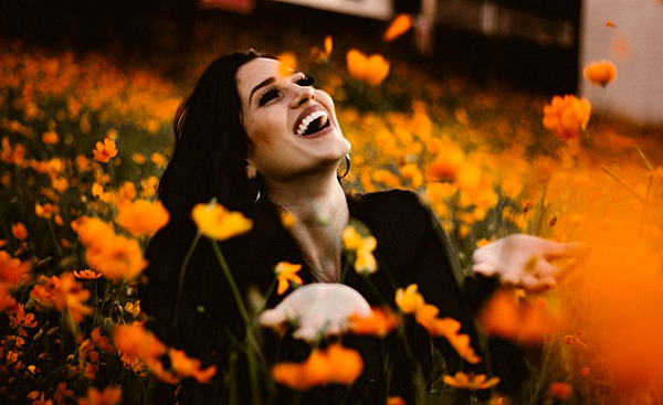 a woman laughing in a field of bright orange flowers