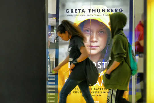 People walk past a poster for Greta Thunberg’s book in Italy. 