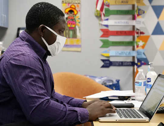 Teaching assistant Samuel Lavi works with an online class at the Valencia Newcomer School, Sept. 2, 2020, in Phoenix. (four steps to teacher recovery from compassion fatigue and burnout)